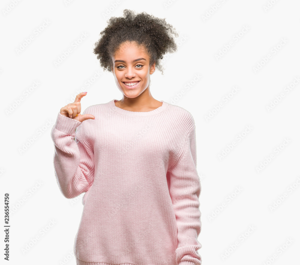 Young afro american woman wearing winter sweater over isolated background smiling and confident gesturing with hand doing size sign with fingers while looking and the camera. Measure concept. Young afro american woman wearing winter sweater over isolated background smiling and confident gesturing with hand doing size sign with fingers while looking and the camera. Measure concept.