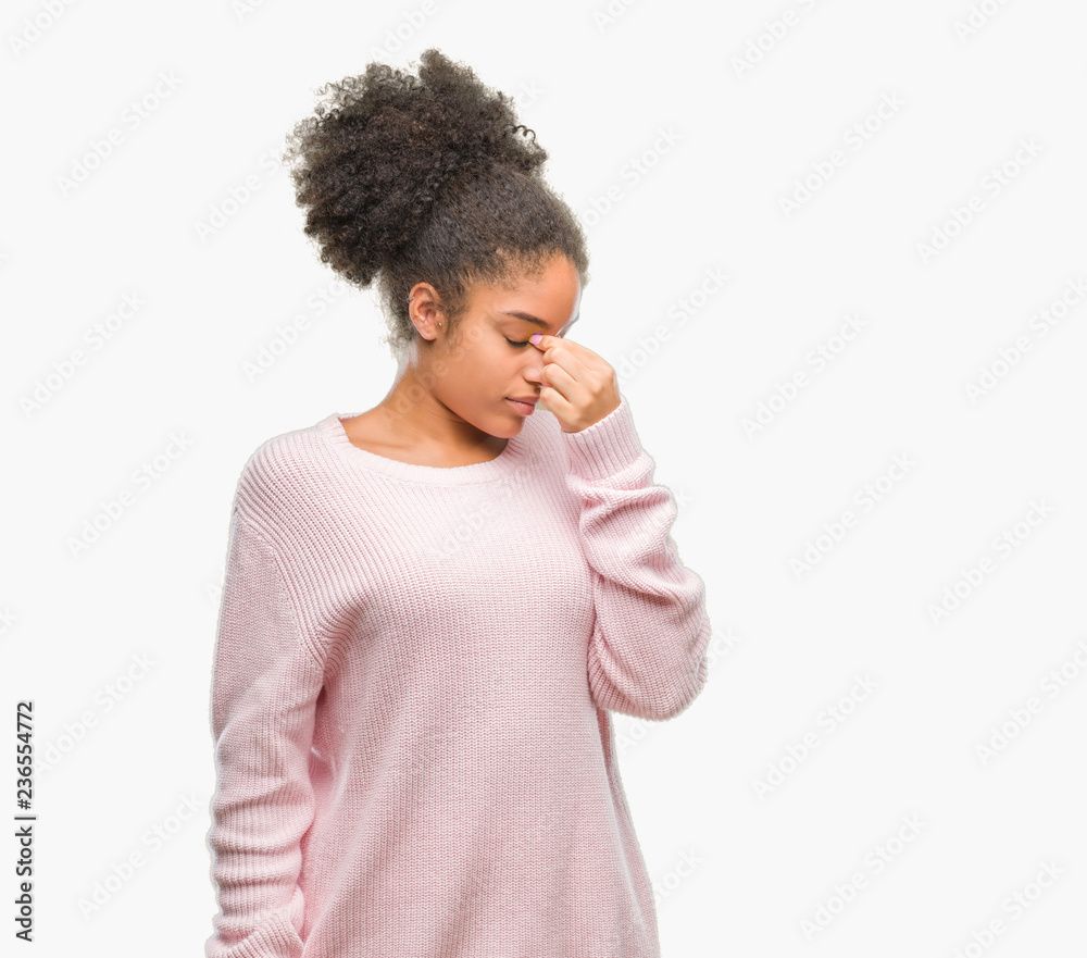 Young afro american woman wearing winter sweater over isolated background tired rubbing nose and eyes feeling fatigue and headache. Stress and frustration concept. Young afro american woman wearing winter sweater over isolated background tired rubbing nose and eyes feeling fatigue and headache. Stress and frustration concept.