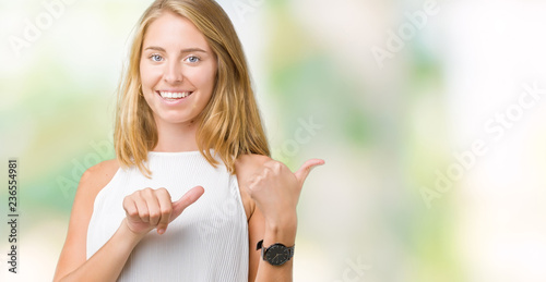 Fototapeta Naklejka Na Ścianę i Meble -  Beautiful young elegant woman over isolated background Pointing to the back behind with hand and thumbs up, smiling confident