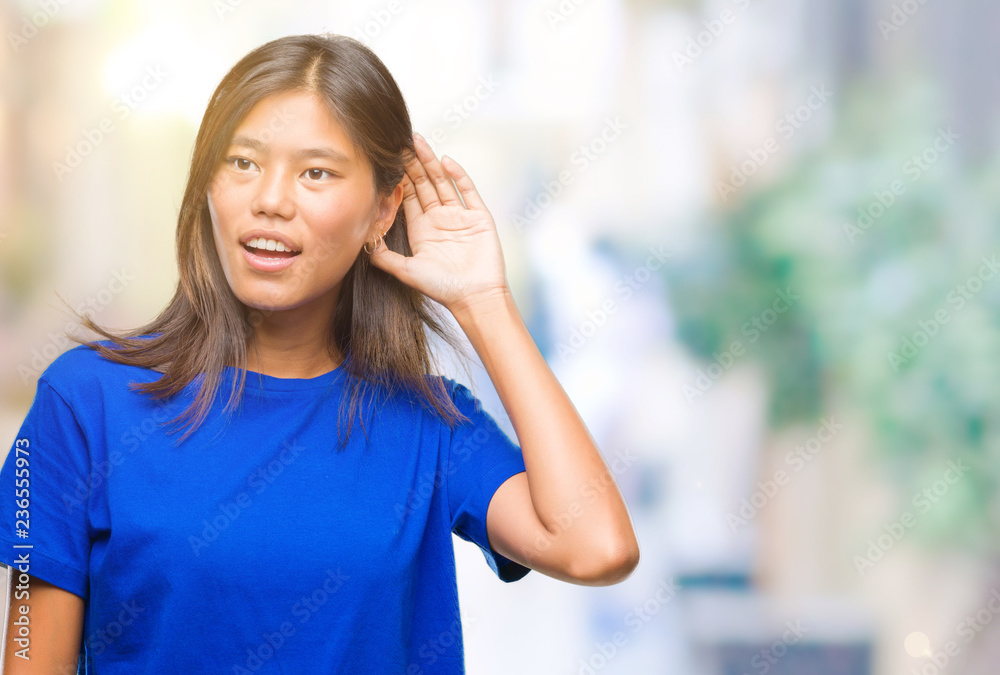 Young asian woman over isolated background smiling with hand over ear listening an hearing to rumor or gossip. Deafness concept. Young asian woman over isolated background smiling with hand over ear listening an hearing to rumor or gossip. Deafness concept.