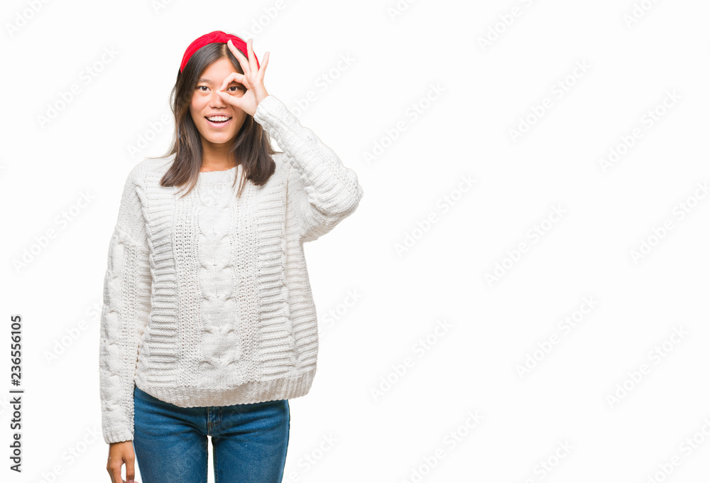 Young asian woman wearing winter sweater over isolated background doing ok gesture with hand smiling, eye looking through fingers with happy face. Young asian woman wearing winter sweater over isolated background doing ok gesture with hand smiling, eye looking through fingers with happy face.