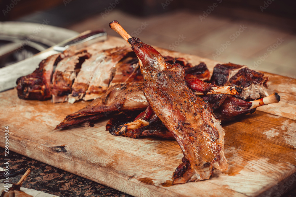 Cutting grilled lamb on wooden table with knife. Top view. Hot Meat dishes