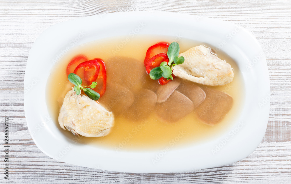 Homemade jelly chicken decorated with greens and eggs on plate on wooden background close up. Cold Meat Dishes Homemade jelly chicken decorated with greens and eggs on plate on wooden background close up. Cold Meat Dishes