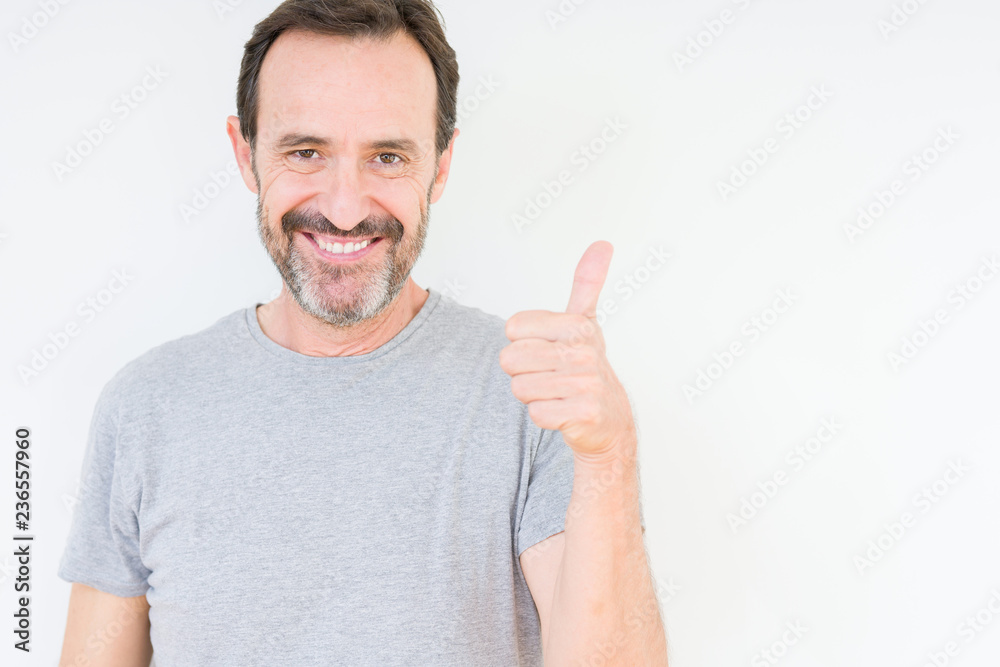 Handsome senior man over isolated background doing happy thumbs up gesture with hand. Approving expression looking at the camera with showing success. Handsome senior man over isolated background doing happy thumbs up gesture with hand. Approving expression looking at the camera with showing success.