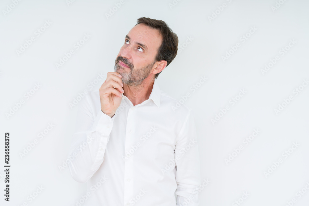 Elegant senior man over isolated background with hand on chin thinking about question, pensive expression. Smiling with thoughtful face. Doubt concept. Elegant senior man over isolated background with hand on chin thinking about question, pensive expression. Smiling with thoughtful face. Doubt concept.
