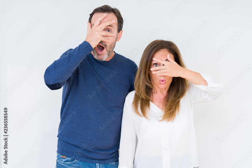 Beautiful middle age couple in love over isolated background peeking in shock covering face and eyes with hand, looking through fingers with embarrassed expression. Beautiful middle age couple in love over isolated background peeking in shock covering face and eyes with hand, looking through fingers with embarrassed expression.