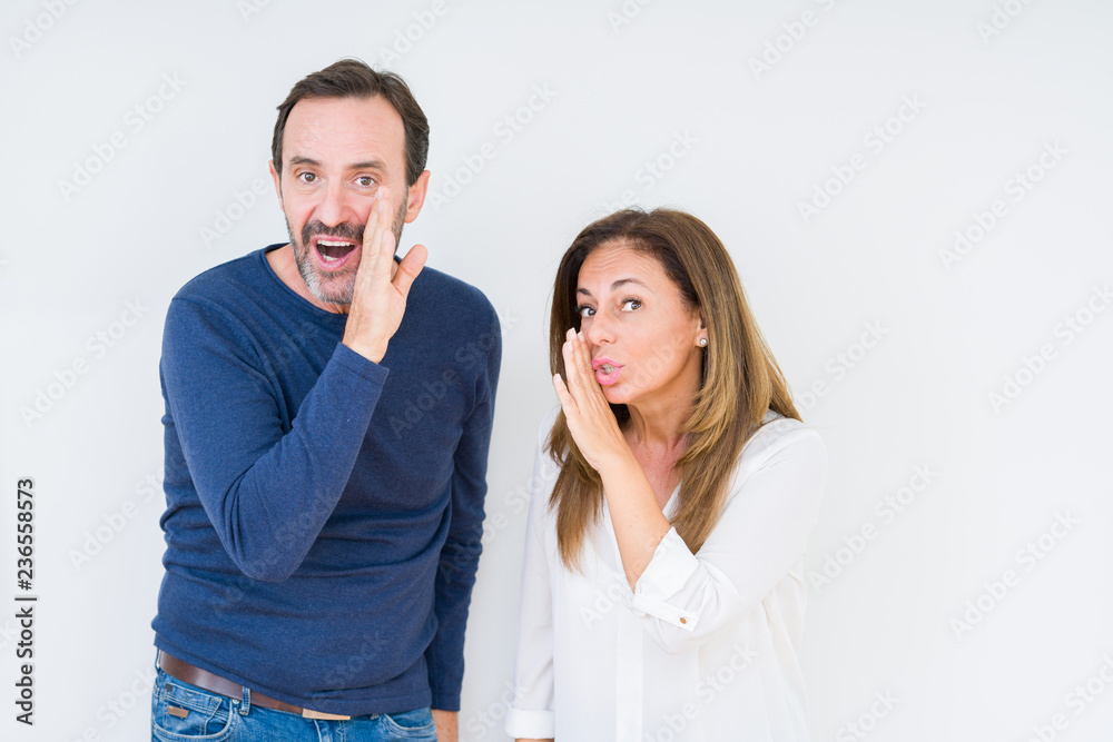 Beautiful middle age couple in love over isolated background hand on mouth telling secret rumor, whispering malicious talk conversation Beautiful middle age couple in love over isolated background hand on mouth telling secret rumor, whispering malicious talk conversation