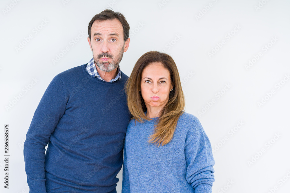 Beautiful middle age couple in love over isolated background puffing cheeks with funny face. Mouth inflated with air, crazy expression. Beautiful middle age couple in love over isolated background puffing cheeks with funny face. Mouth inflated with air, crazy expression.