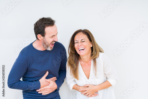 Beautiful middle age couple in love over isolated background Smiling and laughing hard out loud because funny crazy joke. Happy expression.