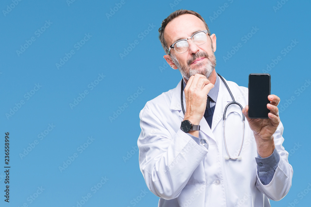 Middle age senior hoary doctor man showing smartphone screen over isolated background serious face thinking about question, very confused idea Middle age senior hoary doctor man showing smartphone screen over isolated background serious face thinking about question, very confused idea