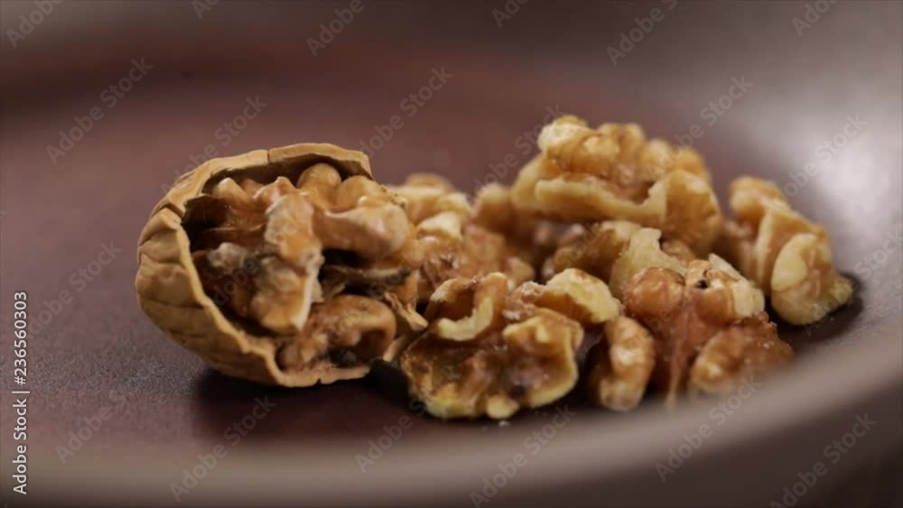 A Half Walnut in Shell and ome Peeled Walnuts Lying in a Pan, still, Closeup A Half Walnut in Shell and ome Peeled Walnuts Lying in a Pan, still, Closeup