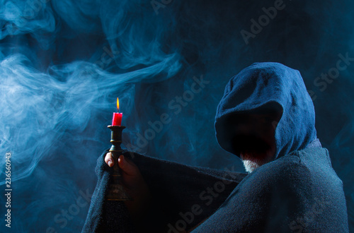 a scary man holds a candle in his hand photo