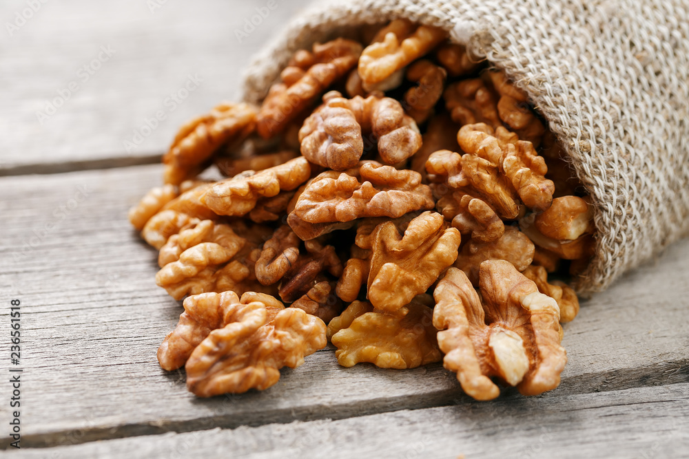 Walnuts in a burlap bag on a wooden gray background. Walnuts in a burlap bag on a wooden gray background.