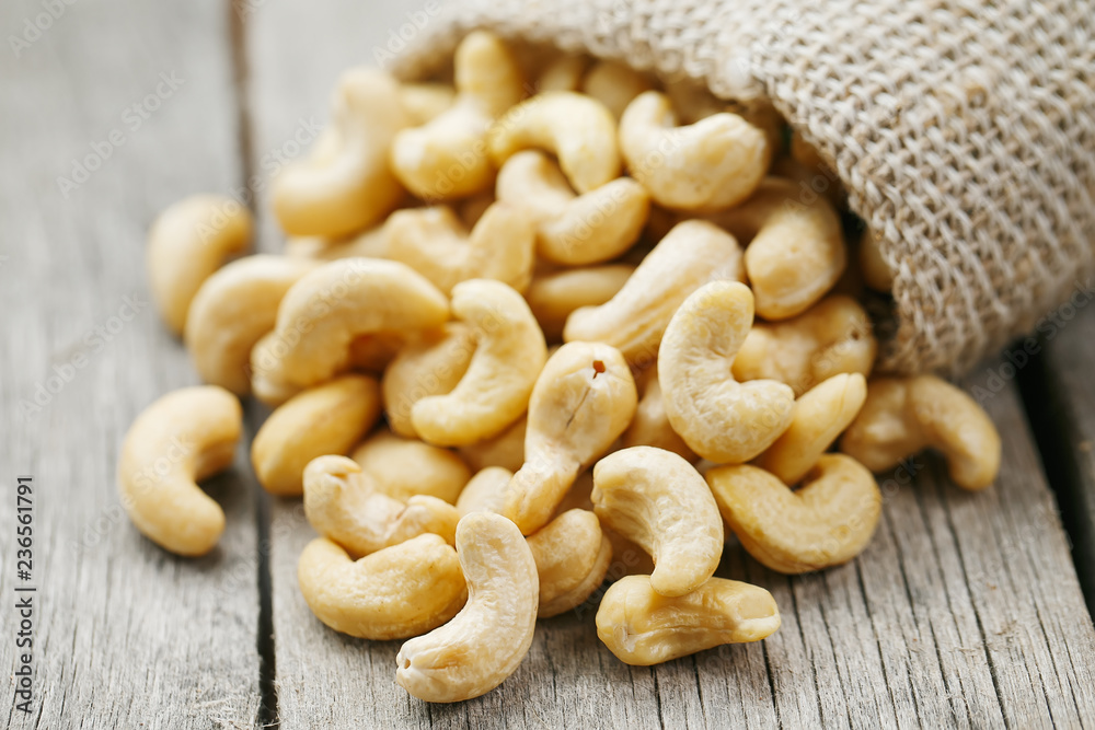 Cashew nuts in burlap bag on wooden gray background . Healthy food Cashew nuts in burlap bag on wooden gray background . Healthy food
