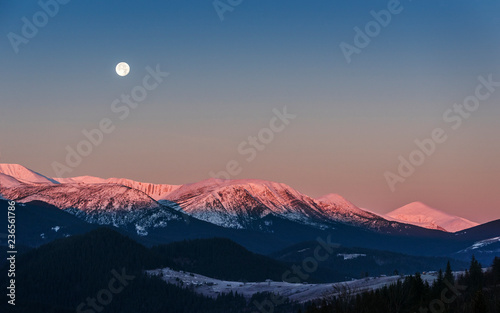 Full moon above the sunrise snow mountain peaks  photo