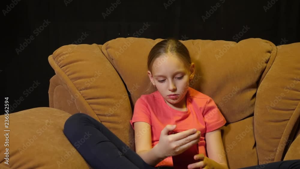 Relaxing teenager girl using smartphone in cozy chair in home living room Relaxing teenager girl using smartphone in cozy chair in home living room