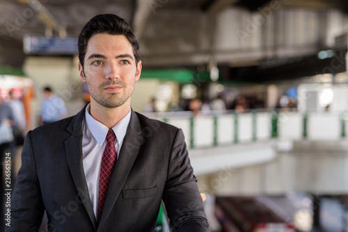 Portrait of young handsome businessman wearing suit in city
