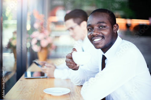 African business man holding a cup of coffee with asian friends