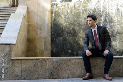 Portrait of young handsome businessman sitting outdoors