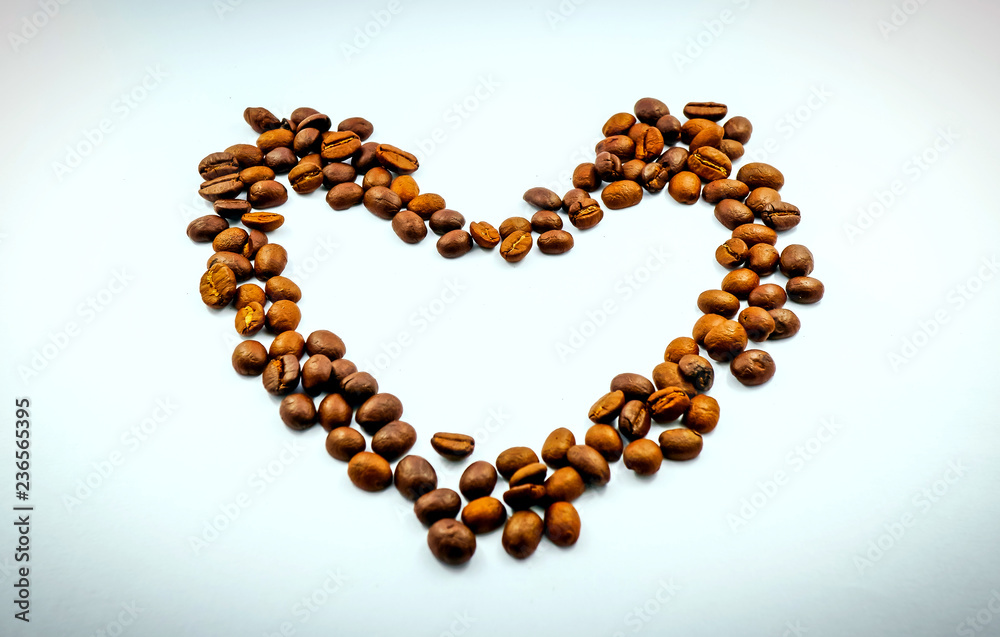 The heart is made of coffee beans on a white background, the side edges are made of dark margins. Leave space for adding text. The heart is made of coffee beans on a white background, the side edges are made of dark margins. Leave space for adding text.
