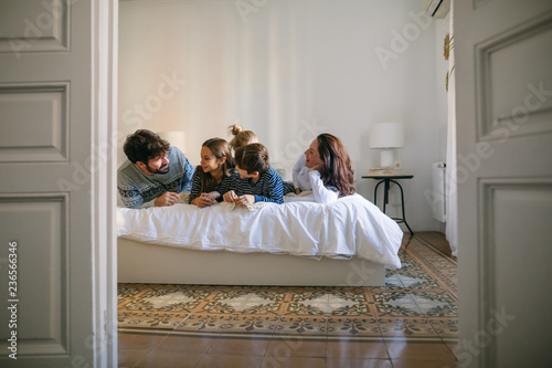 Family wearing pajama resting on bed. 