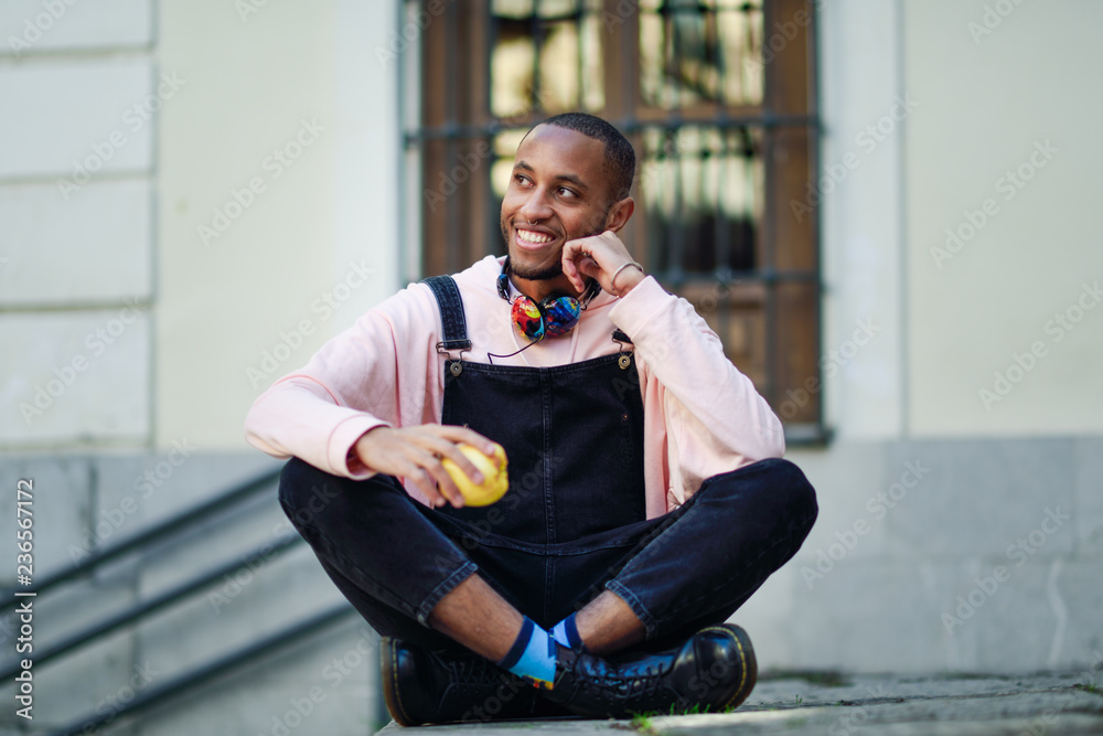 Young black man eating an apple sitting on urban steps. Stock Photo ...