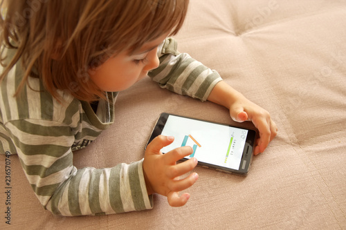 Cute kid girl play game on smart phone