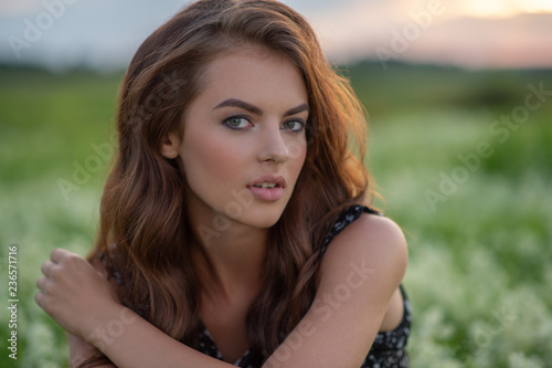 Young woman sitting outdoors in a field of white flowers. © Valua Vitaly