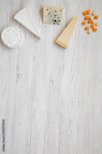 Various kinds of cheeses on white wooden background, overhead view.