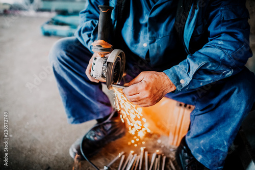 close up industrial workers hands cutting iron with angle grinder