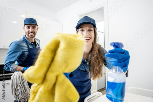 Funny portrait of a man and woman as aprofessional cleaner with cleaning tools in the white apartment interior photo