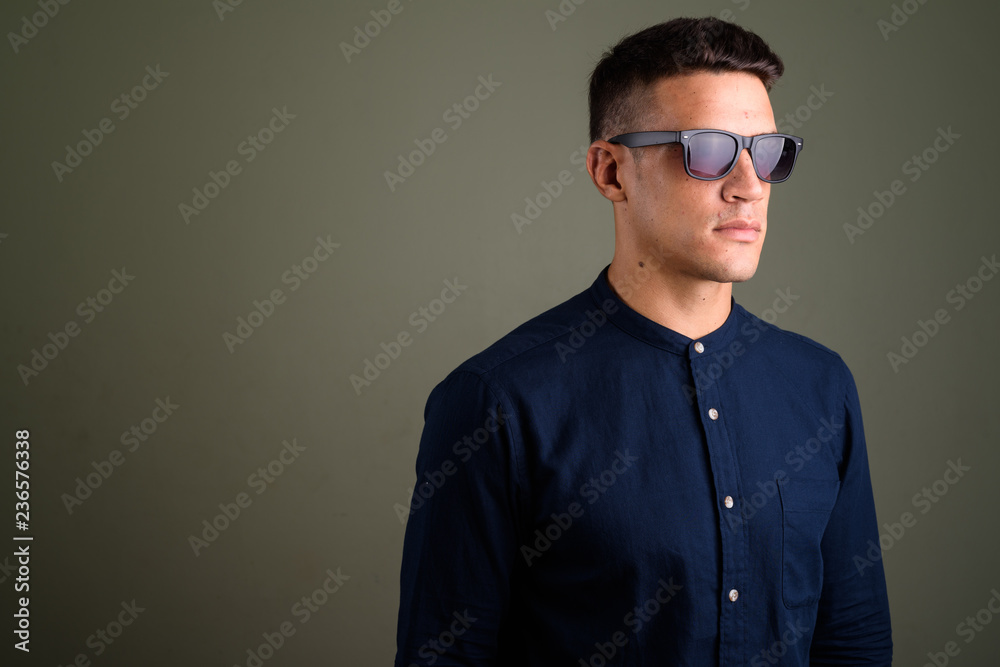 Obraz premium Young handsome businessman wearing sunglasses against colored ba