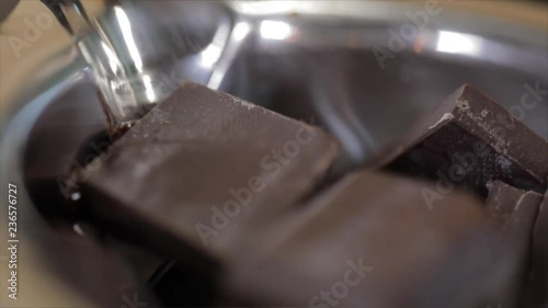 Chocolate Broken into rough Blocks Melts slowly in a stainless steel Crucible, Closeup