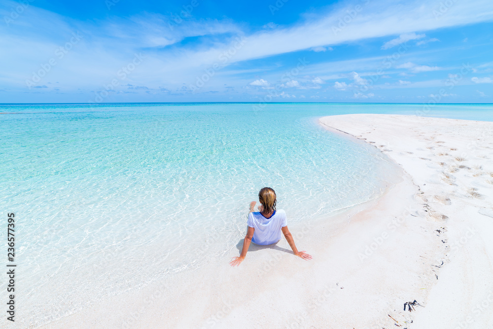 Woman sunbathing on scenic white sand beach, rear view, sunny day, turquoise transparent water, real people. Indonesia, Wakatobi islands Woman sunbathing on scenic white sand beach, rear view, sunny day, turquoise transparent water, real people. Indonesia, Wakatobi islands