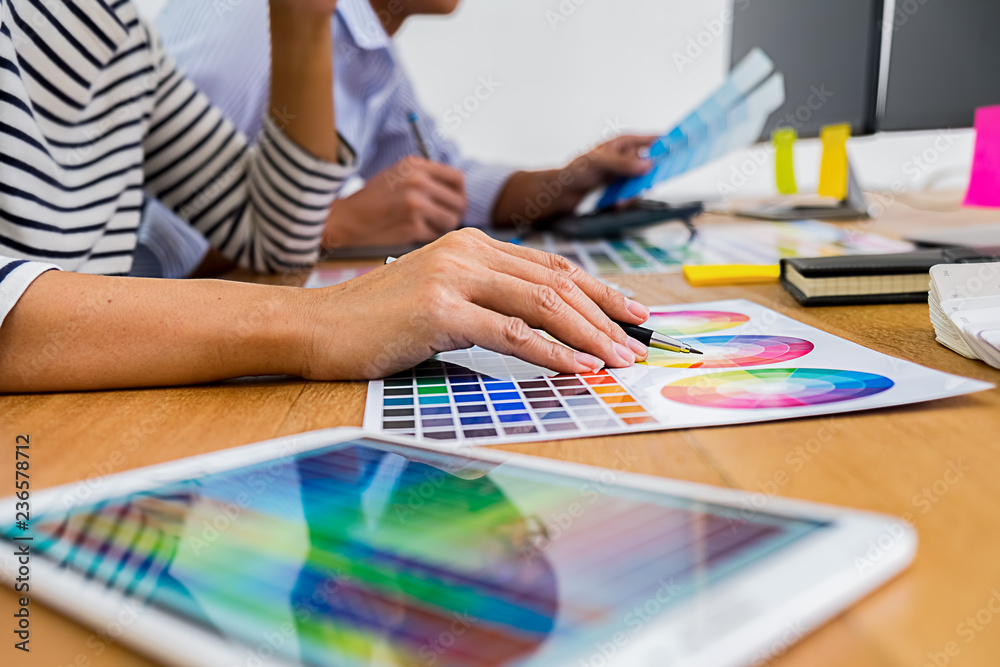 Graphic design with color swatches and tablet on a desk. Graphic designer drawing something on tablet at the office with work tools and accessories. Graphic design with color swatches and tablet on a desk. Graphic designer drawing something on tablet at the office with work tools and accessories.