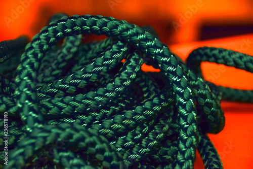 synthetic rope close up in front of orange background, new green rope macro shot for the shipping or health or sports industry