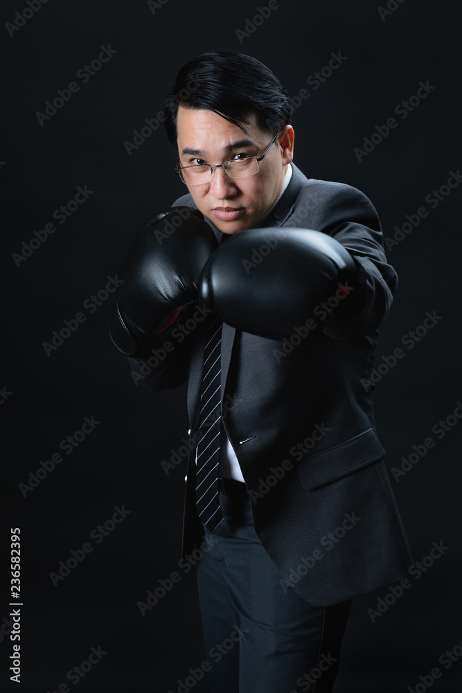 Asian man in suit wearing boxing gloves.
