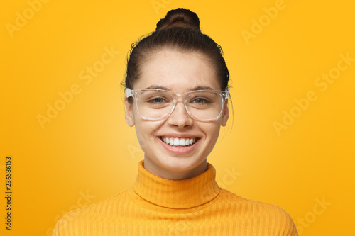 Close up shot of smiling attractive young woman isolated on yellow background