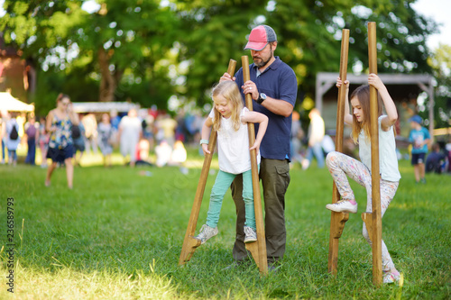 Father and children walking on stilts during annual Medieval Festival, held in Trakai Peninsular Castle.