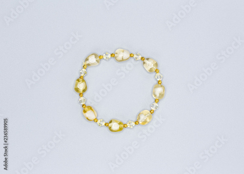 pale yellow colored and variously sized beads bracelet on gray background
