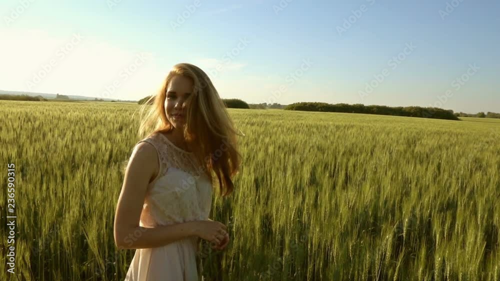 Beautiful girl walking in a wheat field at sunset, slow motion Beautiful girl walking in a wheat field at sunset, slow motion