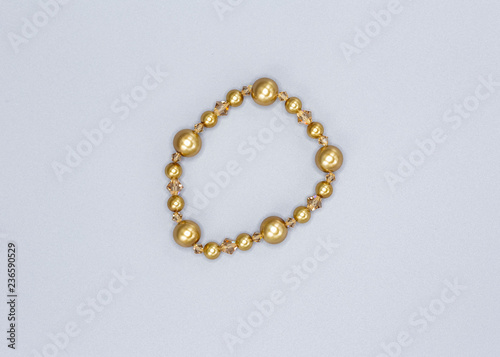 gold colored and variously sized beads bracelet on gray background