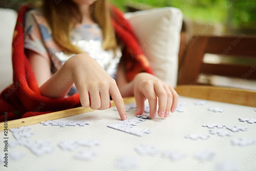 Close-up on child's hands assembling a jigsaw puzzle on a table Close-up on child's hands assembling a jigsaw puzzle on a table