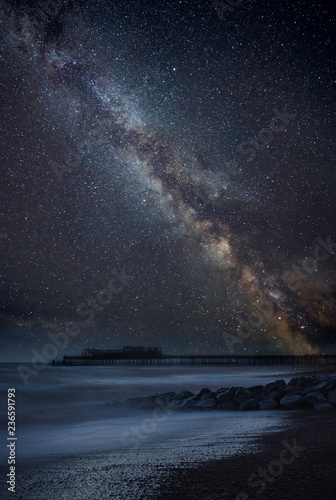 Vibrant Milky Way composite image over landscape of abandoned pier at sea