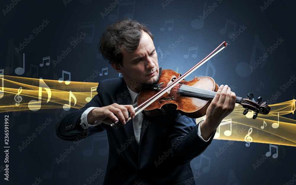 Fototapeta premium Young male musician playing on his violin with musical notes around