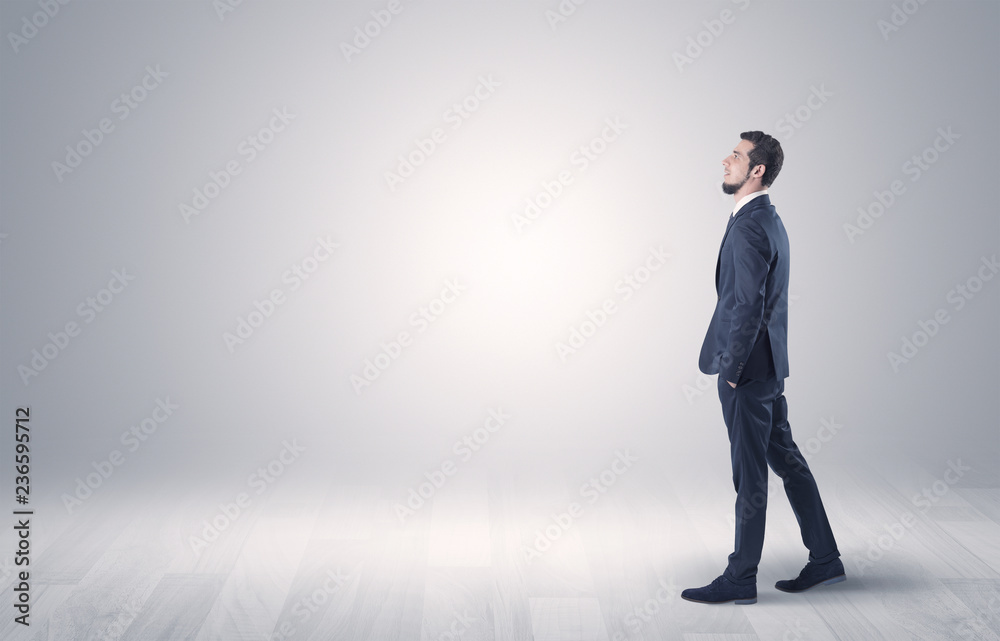 Successful businessman walking in front of an empty wall with briefcase on his hand
Successful businessman walking in front of an empty wall with briefcase on his hand