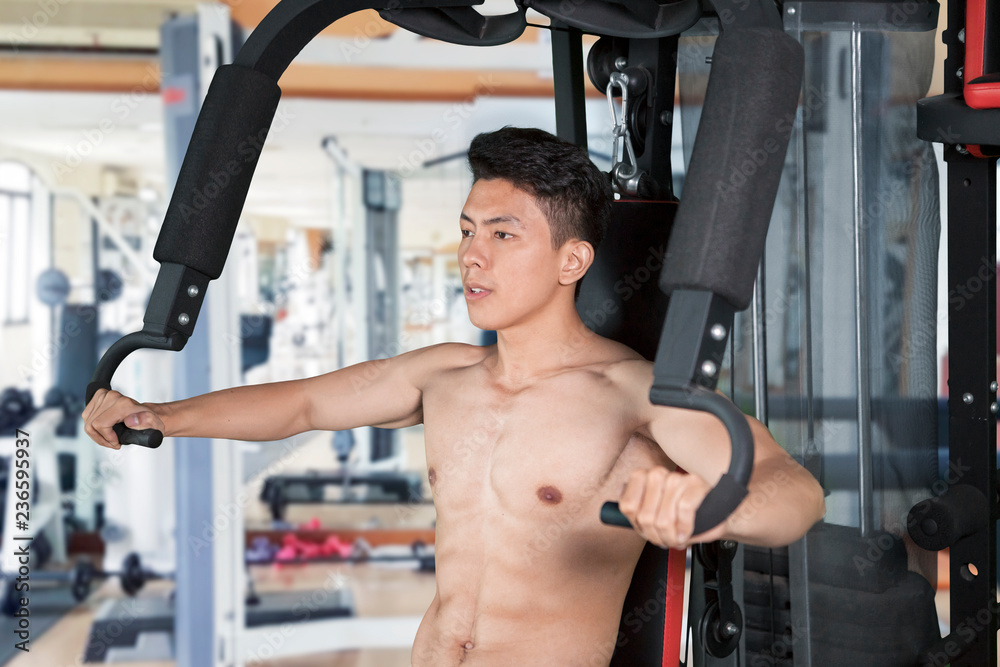 Fototapeta premium Muscular man exercising with fitness machine