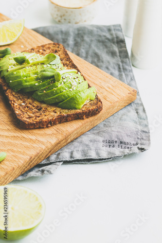 Toast with avocado on a wooden board on a breakfast table. The concept of vegetarian and healthy diet food. Copy space.