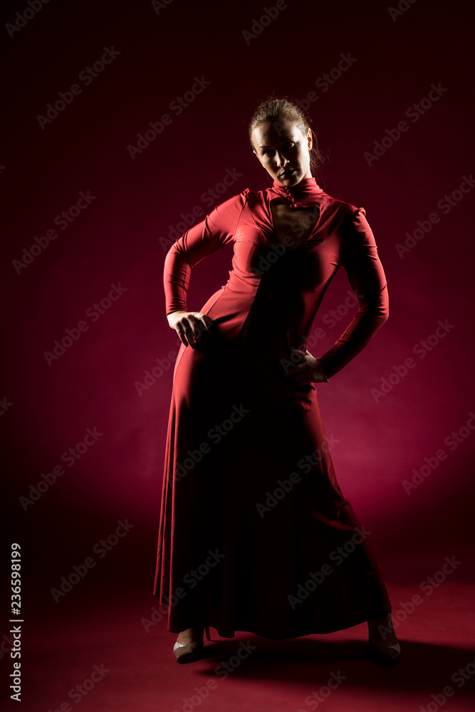 Lady in red gown standing and posing  in studio. Portrait of beautiful elegant woman in evening dress