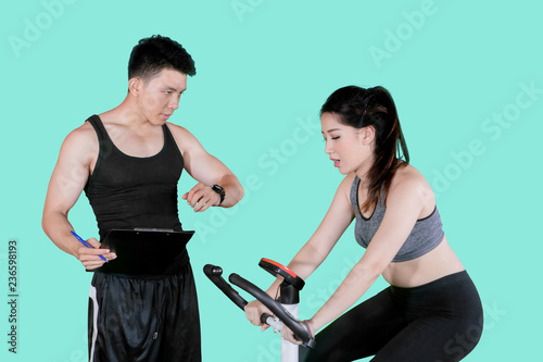 Trainer timing his client during exercise on studio